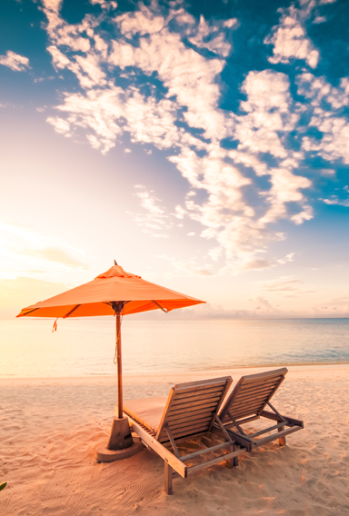 Beach furniture next to ocean at sunset