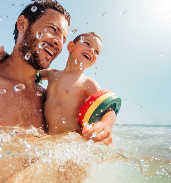 Man and child swimming on beach